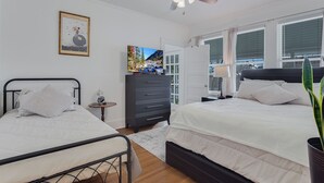 A bedroom with two beds, a ceiling fan, a TV, and a dresser.