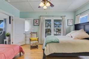 Ein Schlafzimmer mit zwei Betten, einem Deckenventilator und Blick ins Freie.