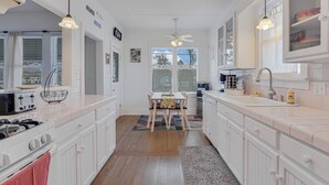A spacious kitchen with white cabinetry, a central island, and a dining area.