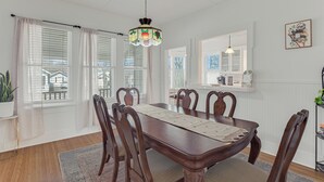 A dining room with a wooden table, chairs, and a hanging light fixture.