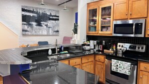 A modern kitchen with a curved granite countertop, stainless steel appliances, and wooden cabinets. - Richmond City Skyline View with free parking (Richmond)