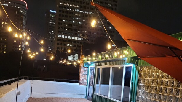 A rooftop deck with outdoor seating, a fire feature, and string lights. - Richmond City Skyline View with free parking (Richmond)
