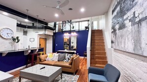 A spacious living area with a high ceiling, a modern kitchen, a dining area, and a staircase leading to an upper level. - Richmond City Skyline View with free parking (Richmond)