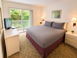 A bedroom with a bed, bedside tables, a TV, and a balcony with a view of greenery. - Comfortable Home at Berkley Resort (Kissimmee)