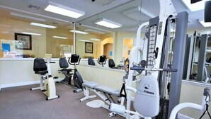 A gym with various exercise machines, a bench, and a mirrored wall. - Comfortable Home at Berkley Resort (Kissimmee)