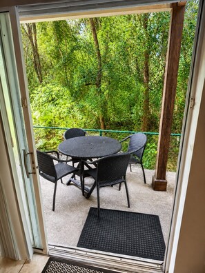 A glass door leading to an outdoor patio with a round table and chairs, surrounded by lush greenery. - Comfortable Home at Berkley Resort (Kissimmee)