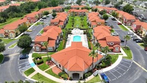 A residential area with multiple houses, a central building with a swimming pool, and a curved road layout. - Comfortable Home at Berkley Resort (Kissimmee)