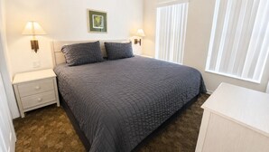 A bedroom with a bed, nightstands, wall-mounted lamps, a framed picture, and a window with blinds. - The Ideal Getaway V | 3BR near Disney & Pool (Kissimmee)