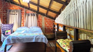 Une chambre mansardée chaleureuse avec un plafond en bois, un lit, un fauteuil suspendu et un hamac.