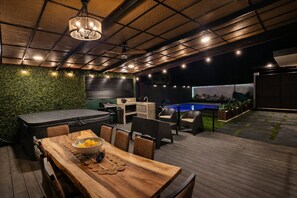 An outdoor patio area with a wooden table, chairs, a grill, and a pool. - Oasis Luxe Villa - Private Hot Tub and Swimming Pool! (La Fortuna)