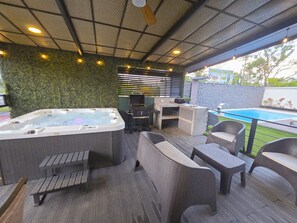 Ein Whirlpool, Sitzgelegenheiten im Freien, ein Grill und ein Pool.