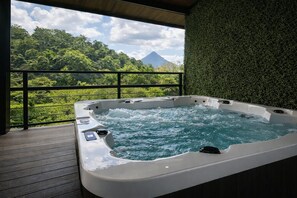 Uma banheira de hidromassagem em uma varanda com vista para uma montanha e vegetação exuberante.