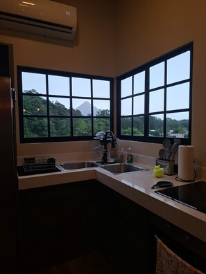 A kitchen with two sinks, a stove, and a window with a view of a mountain. - Oasis Luxe Villa - Private Hot Tub and Swimming Pool! (La Fortuna)