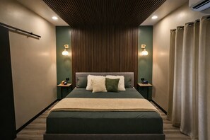 Une chambre moderne avec un grand lit, deux tables de chevet et un climatiseur fixé au mur.