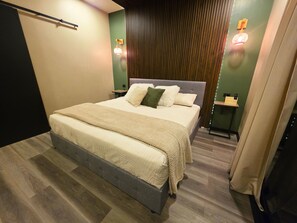 Ein modernes Schlafzimmer mit einem großen Bett, einem Nachttisch, einer Wandlampe und einer Wandverkleidung aus Holz.