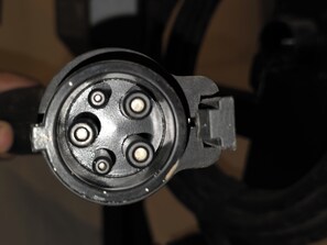Detailaufnahme eines mechanischen Bauteils mit vier kreisförmigen Löchern.