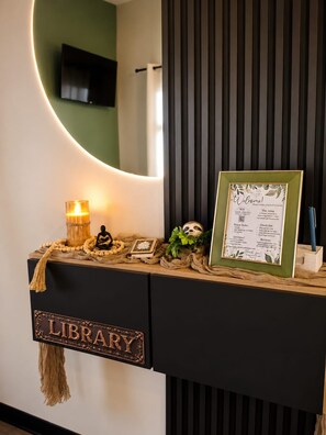 A library desk with a framed welcome sign, a candle, and decorative items. - Oasis Luxe Villa - Private Hot Tub and Swimming Pool! (La Fortuna)