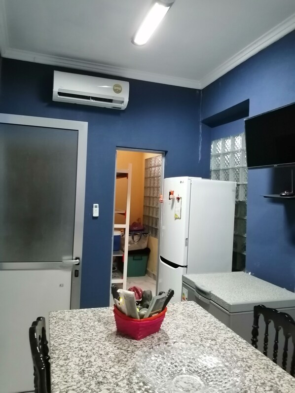 A compact kitchen with a granite countertop, a white refrigerator, and a microwave.