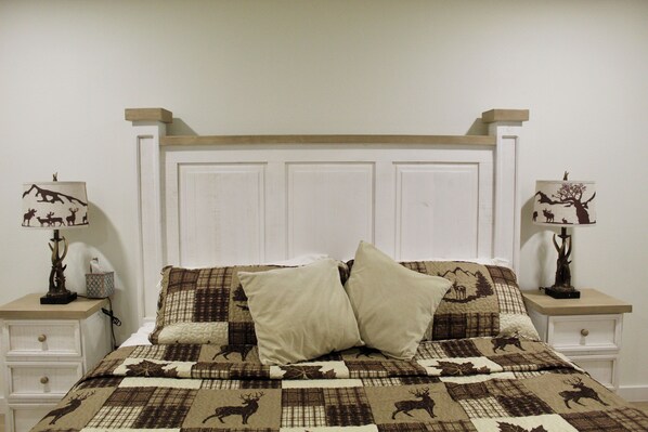 A bedroom with a bed, two nightstands, and two lamps.