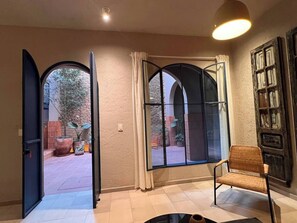 Ein Zimmer mit einem großen Bogenfenster, einem Sessel und einem Bücherregal.