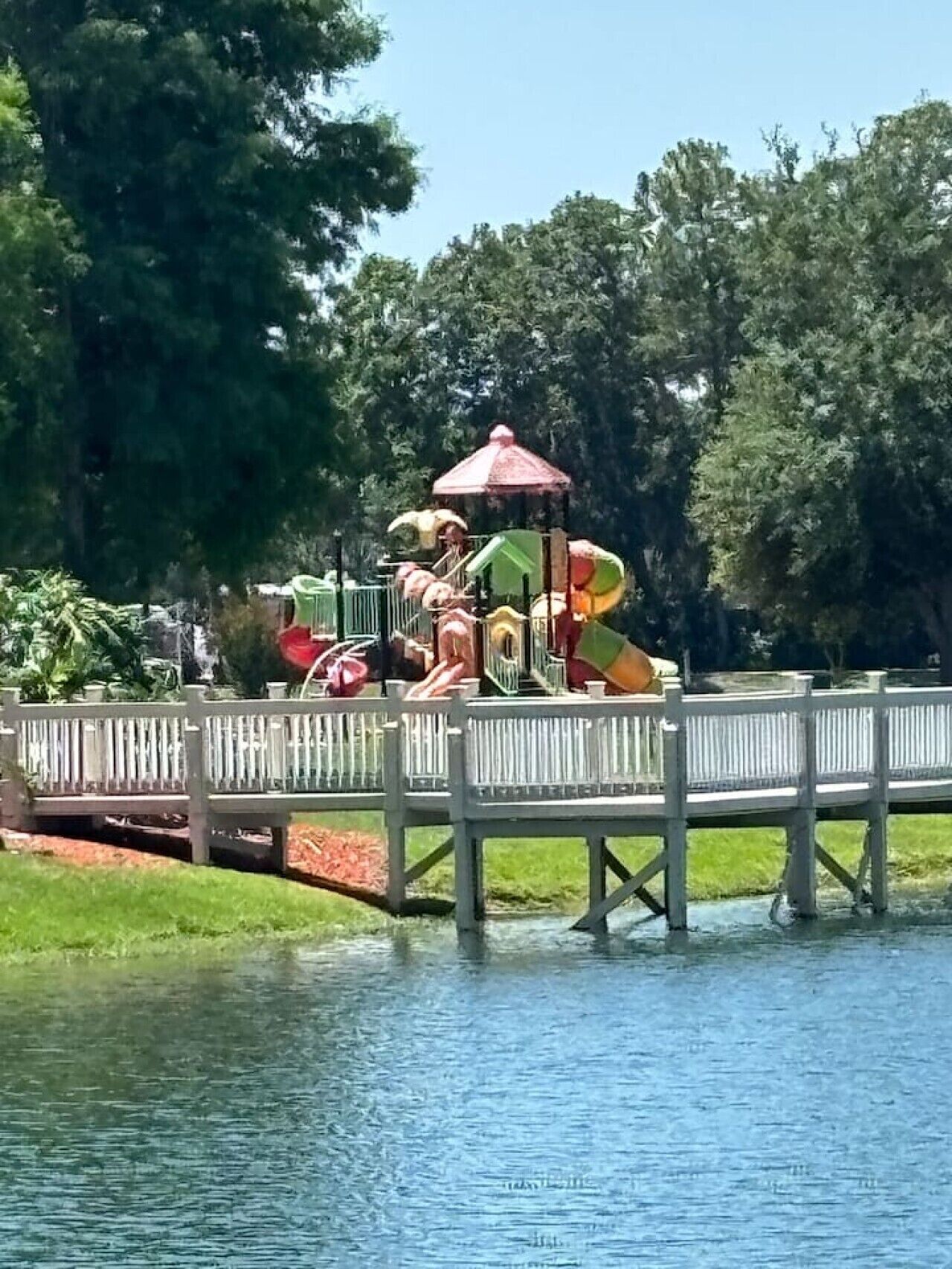 A water park with a play structure and a wooden bridge.