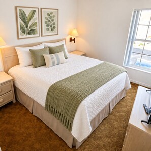 A neatly made bed with a green throw blanket, two bedside lamps, and a window with a view. - Kissimmee Value Townhouse w/ Direct Pool Access (Kissimmee)