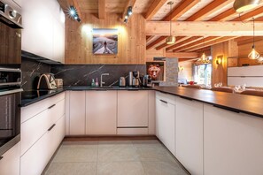 A modern kitchen with wooden beams, a marble countertop, and a large window. - Chalet 14p - Jacuzzi - Lift - Sport - 300m from the slopes - Centre les 2 Alpes (Les Deux Alpes)
