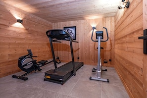 A gym with a treadmill, elliptical, and stationary bike, wooden walls, and a framed picture on the wall. - Chalet 14p - Jacuzzi - Lift - Sport - 300m from the slopes - Centre les 2 Alpes (Les Deux Alpes)