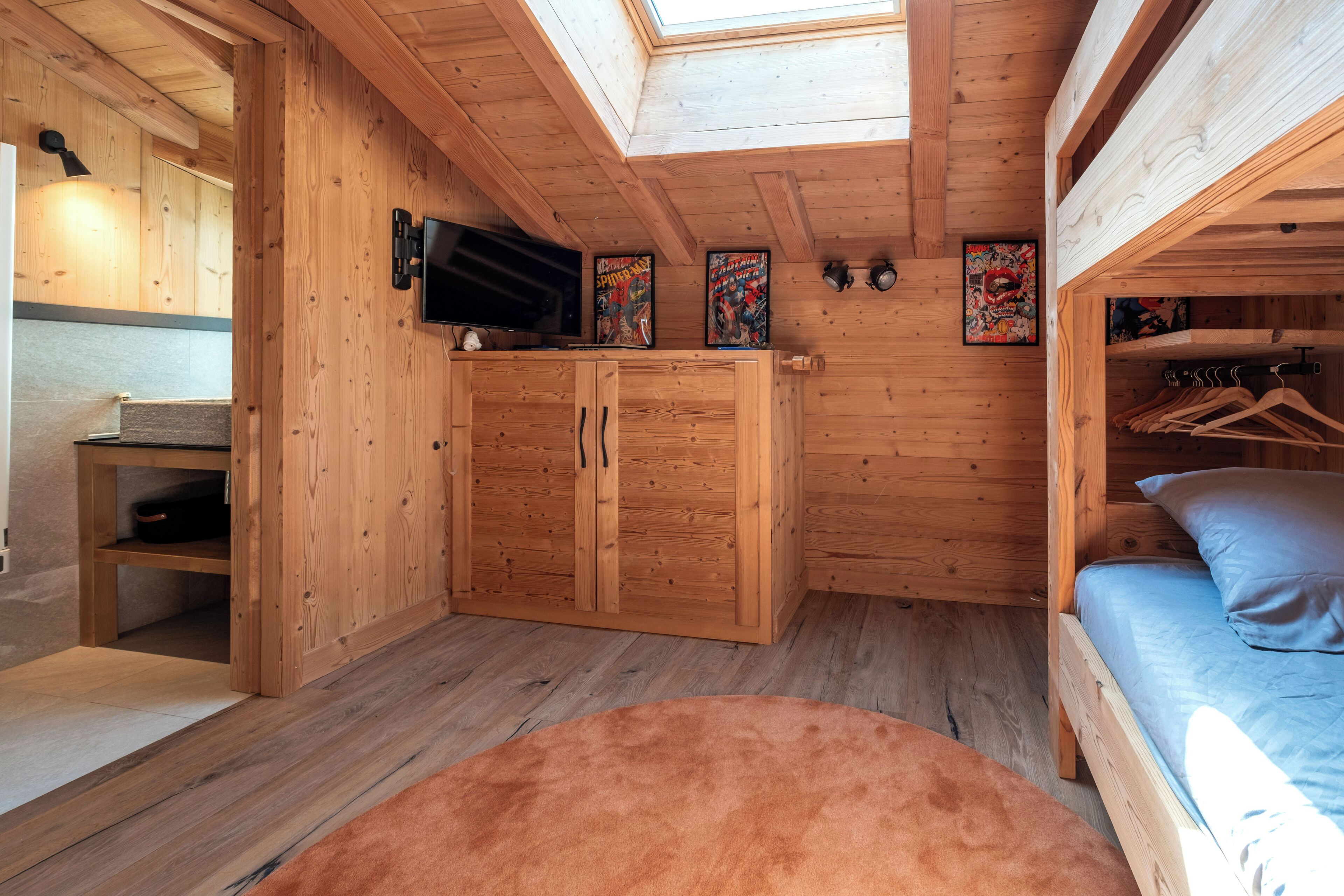 A wooden cabin interior with a bed, a TV, and a closet.