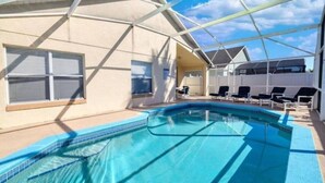 Et poolområde med en klar blå pool, liggestole og en overdækket terrasse.