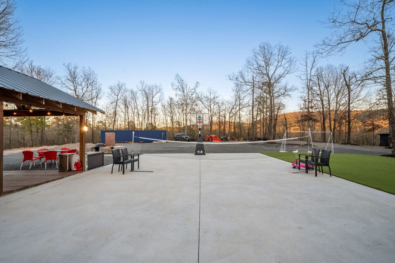 An outdoor patio area with a volleyball net, seating, and a covered section with tables and chairs.