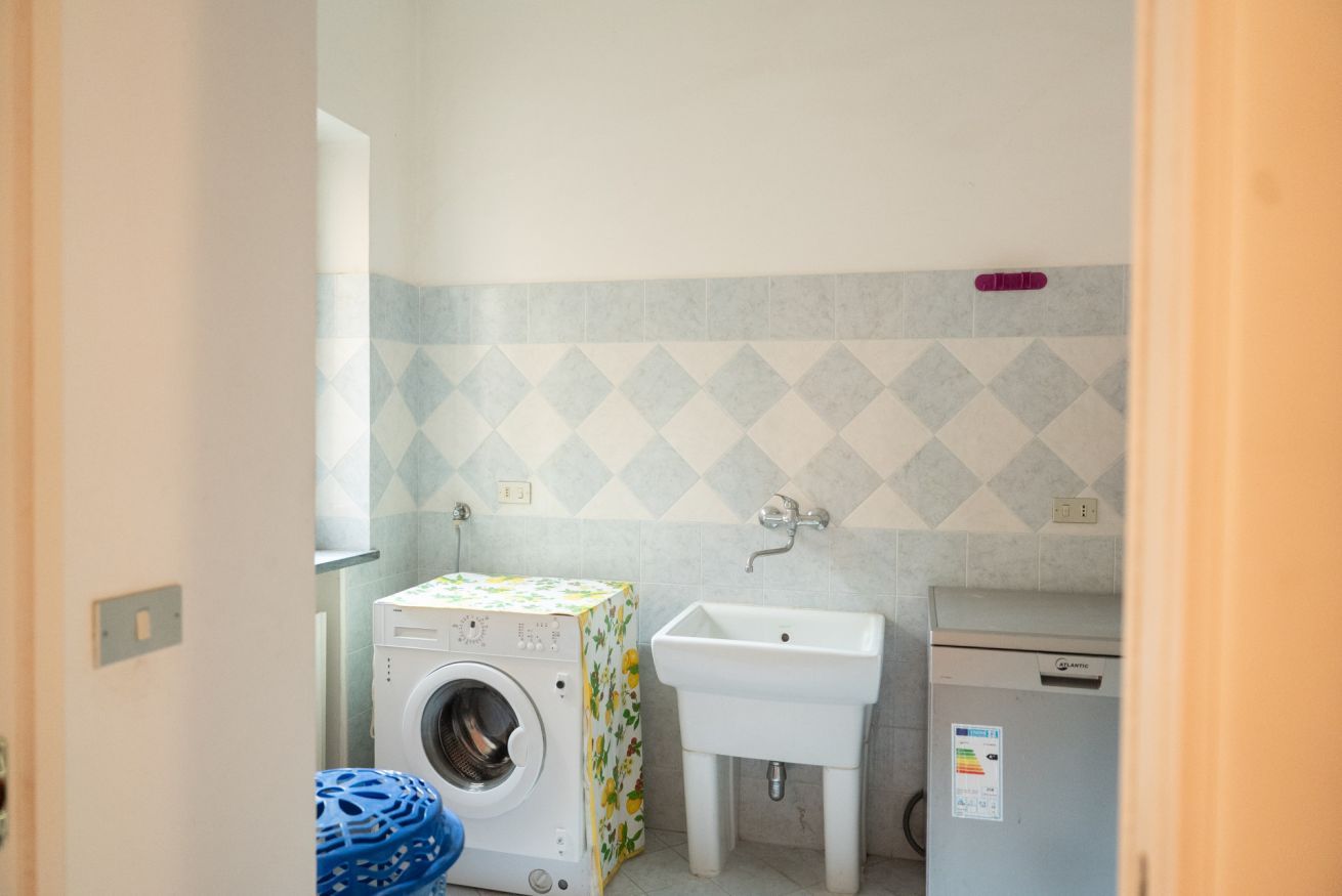 A compact laundry room with a washing machine, a sink, and a small refrigerator.