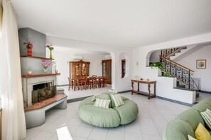 Ein Wohnzimmer mit Kamin, Essbereich und Treppe, sowie einem grünen Sitzsack.