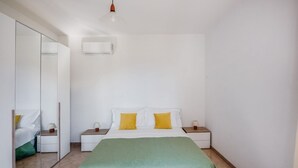 Un dormitorio con cama, mesitas de noche, un espejo y una lámpara colgante.