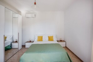 Ein Schlafzimmer mit einem Bett, Nachttischen, einem Spiegel und einer Hängelampe.