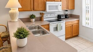 Una cocina moderna con armarios de madera, microondas integrado, estufa y una isla grande con lavamanos.