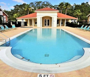 A rectangular pool with a tiled deck, a covered structure with a red roof, and lounge chairs around the pool. - Unlimited Fun 3 (1004) (Kissimmee)