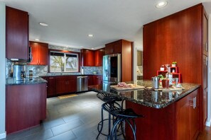 Une cuisine moderne avec des meubles en bois foncé, des appareils électroménagers en acier inoxydable et un plan de travail en granit.