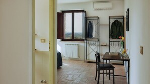 A room with a dining table, chairs, a radiator, and a window with a view. - IL VECCHIO BRACIERE (San Venanzo)