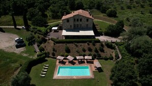 An aerial view of a stone house with a swimming pool, surrounded by a well-maintained lawn and a wooden fence. - IL VECCHIO BRACIERE (San Venanzo)