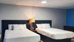 Ett hotellrum med två sängar, ett nattduksbord och en lampa.