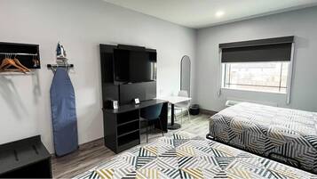 Una habitación de hotel con cama, escritorio, silla, televisión, armario y ventana.