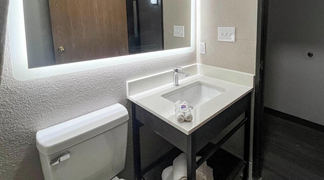 A compact bathroom with a white sink, a mirror, and a toilet.