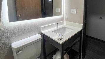 A compact bathroom with a white sink, a mirror, and a toilet.