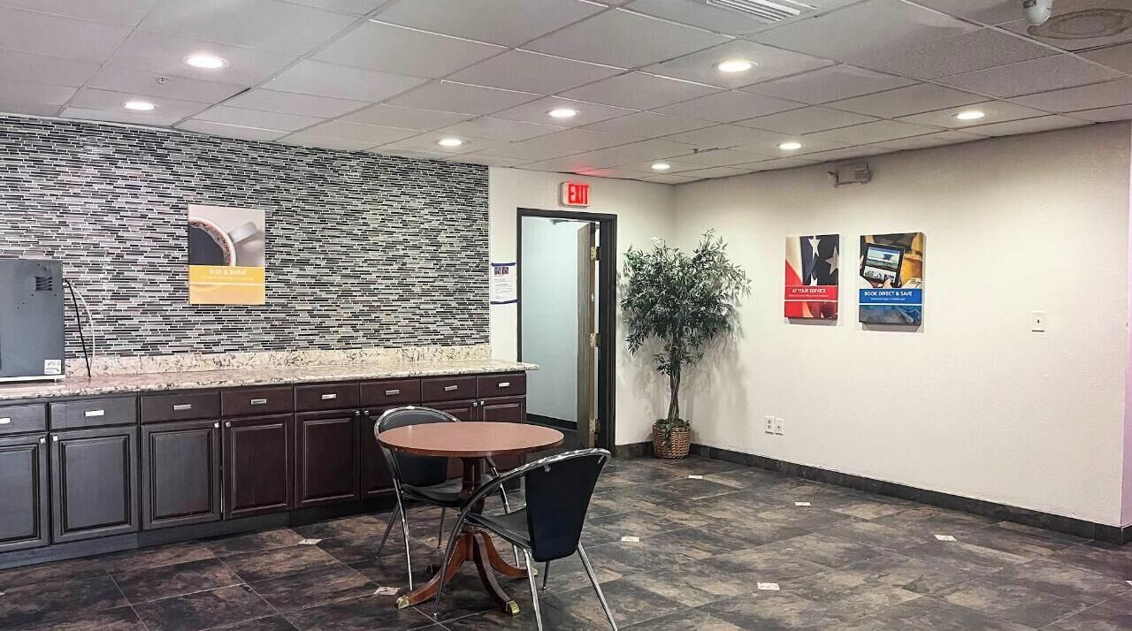 A reception area with a stone wall, a reception desk, a round table with chairs, and a potted plant.