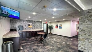 A modern kitchen area with a granite countertop, a sink, and a small island with a chair. - Studio 6 – Mobile, AL (Mobile)
