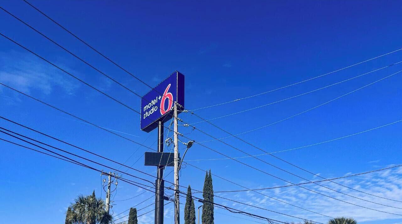 Un letrero azul con el texto "motel 6 studio" contra un cielo azul despejado.