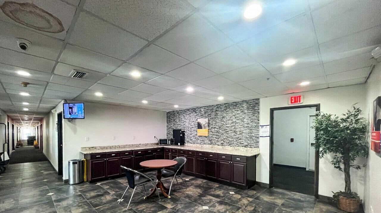 A modern kitchen area with a granite countertop, a sink, a coffee machine, and a small dining table with chairs.