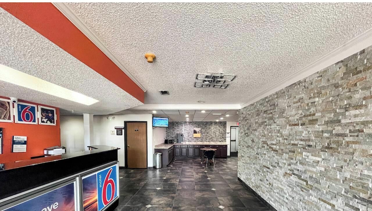 Un vestíbulo con mostrador de recepción, pared de piedra y una pantalla de televisión.