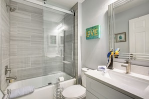 Une salle de bain moderne avec une douche à parois de verre, des toilettes blanches et un lavabo avec un miroir au-dessus.